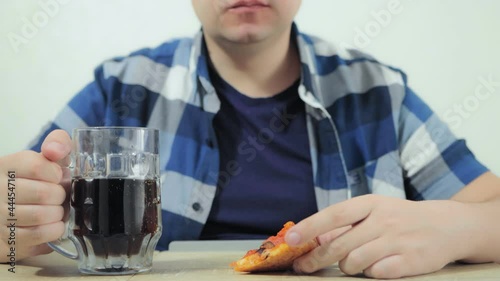 Man is eating pizza, drinking carbonated beverage or dark beer, watching sports channel during soccer football world championship cup on TV. Harmful lifestyle. Depression, loneliness. Weekend. Movie photo