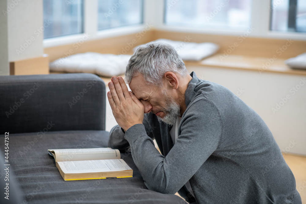 Fototapeta premium A gray-haired man sitting with eyes closed and saying the payers