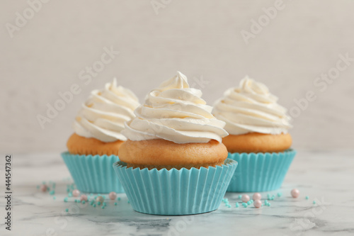 Delicious cupcakes decorated with cream on white marble table