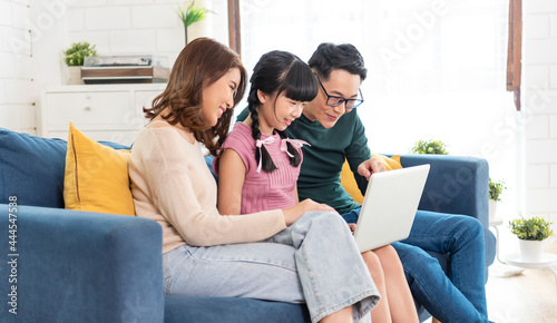 Happy Asian family using computer laptop together on sofa at home living room... photo