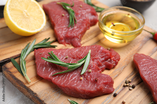 Fresh raw meat steaks and spices on wooden board, closeup