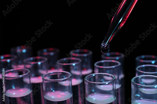 Photography Dripping reagent into test tube on black background, closeup