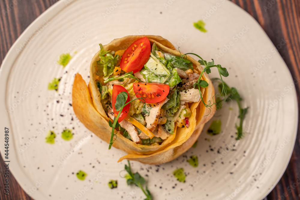 Tortilla with chicken fillet on a beautiful white flat plate Tortilla with chicken fillet on a beautiful white flat plate