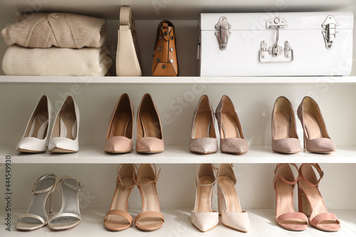 Fotografie Stylish women's shoes, clothes and bags on shelving unit