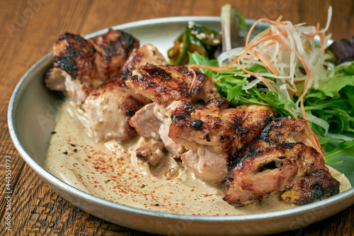 Grilled beef with white barbecue sauce ponzu cucumbers and sauce in a plate on a wooden background