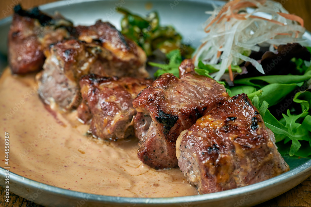 Grilled beef with white barbecue sauce ponzu cucumbers and sauce in a plate on a wooden background Grilled beef with white barbecue sauce ponzu cucumbers and sauce in a plate on a wooden background