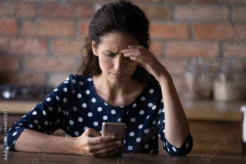 Bilde på lerret Worried Latin woman having problems with mobile phone, using wrong working apps,