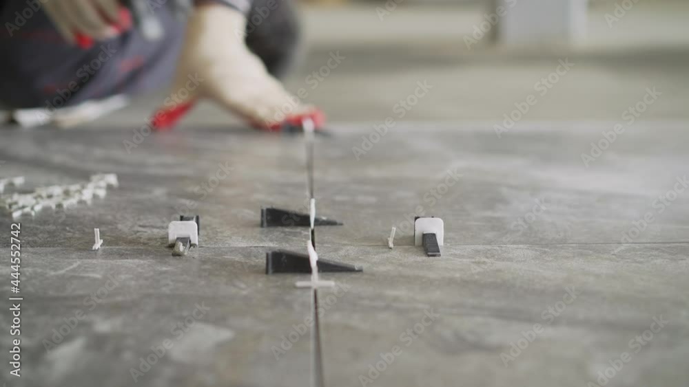 Anchoring crosses to level the tiles on the floor. Installation of crosses and laying of tiles on the floor. Laying the floor with ceramic tiles. Use plastic crosses to align the seams.