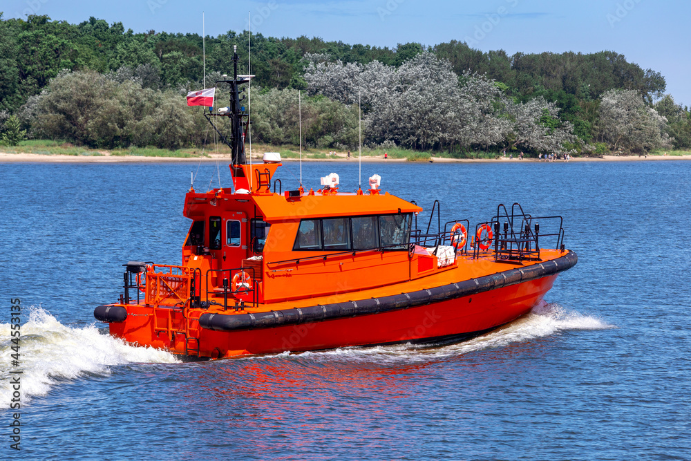 Swinoujscie. The red pilot boat goes along the river.