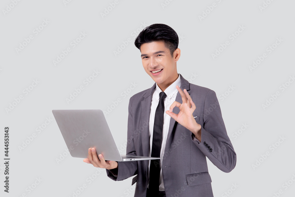 Young asian business man standing work on laptop computer to internet online isolated on white background, businessman confident and notebook, freelance with success, marketing and communication.