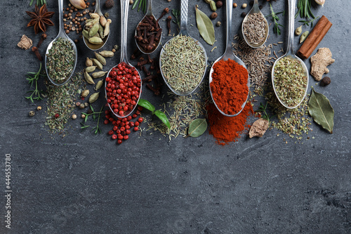 Flat lay composition with different natural spices and herbs on black table, space for text
