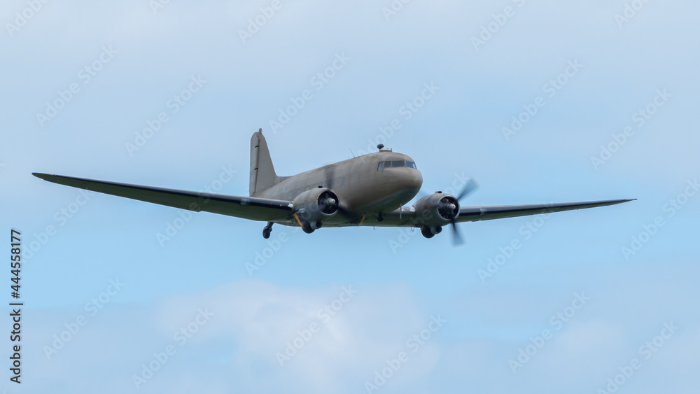 A vintage dakota aircraft in flight with blue sky