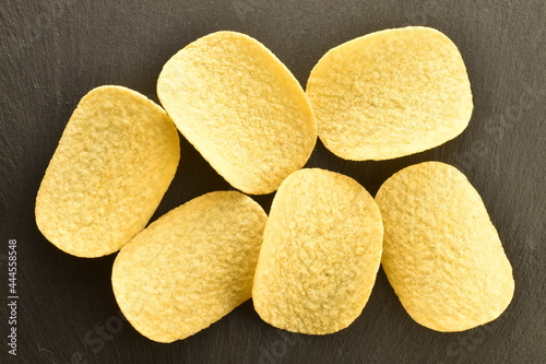 Several potato chips on a serving slate board, close-up, top view.
