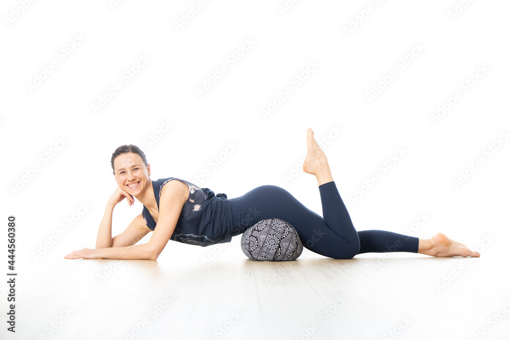 Restorative yoga with a bolster. Young sporty female yoga instructor in bright white yoga studio, lying on bolster cushion, stretching, smilling, showing love and passion for restorative yoga Restorative yoga with a bolster. Young sporty female yoga instructor in bright white yoga studio, lying on bolster cushion, stretching, smilling, showing love and passion for restorative yoga