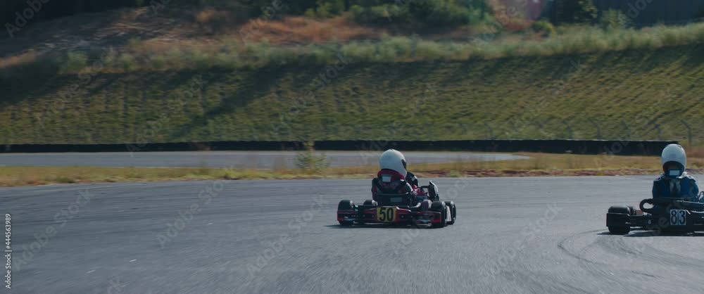 TRACKING Two teenagers pro racers driving their karts on a race track. Shot with 2x anamorphic lens