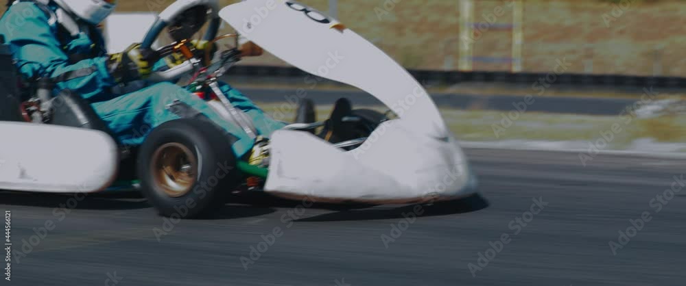 TRACKING Front view of teenager professional racer driving his go kart on a race track. Shot with 2x anamorphic lens