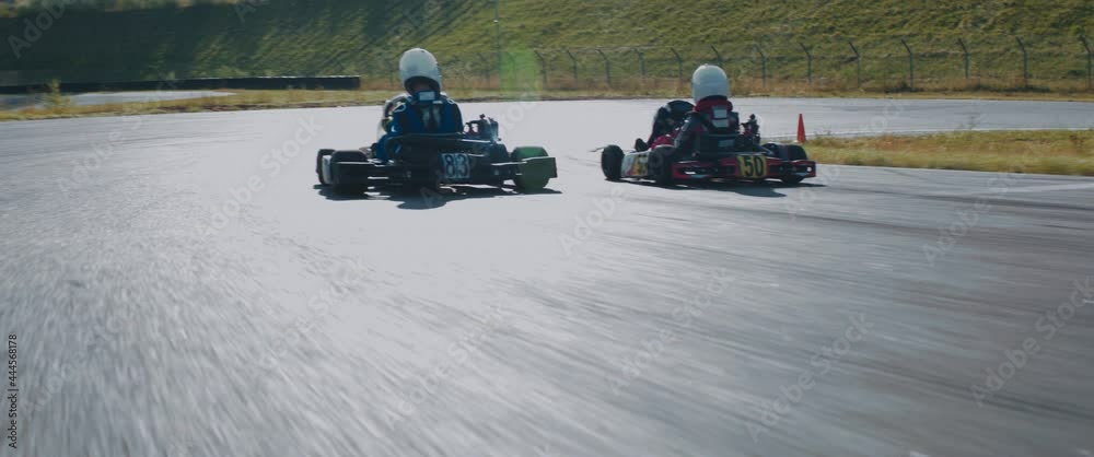 TRACKING Two teenagers pro racers driving their karts on a race track. Shot with 2x anamorphic lens
