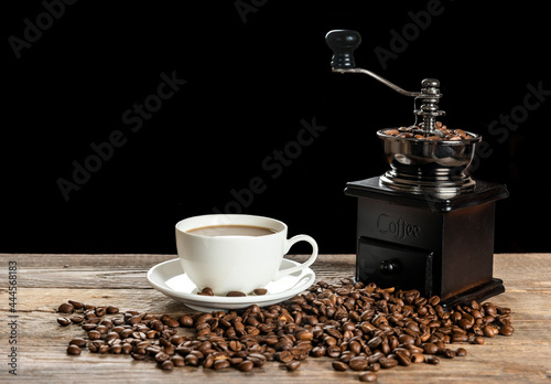 Cup of coffee and manual retro grinder on wooden table