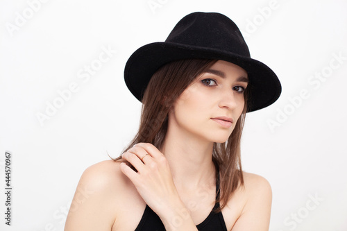 Portrait of a beautiful girl wearing black hat in the studio looking into the camera