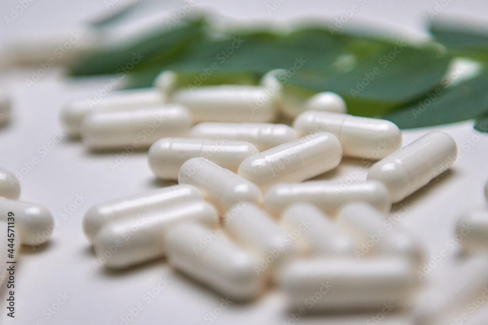 Many white capsule pills on a colorful background. Health supplements and medicines Many white capsule pills on a colorful background. Health supplements and medicines