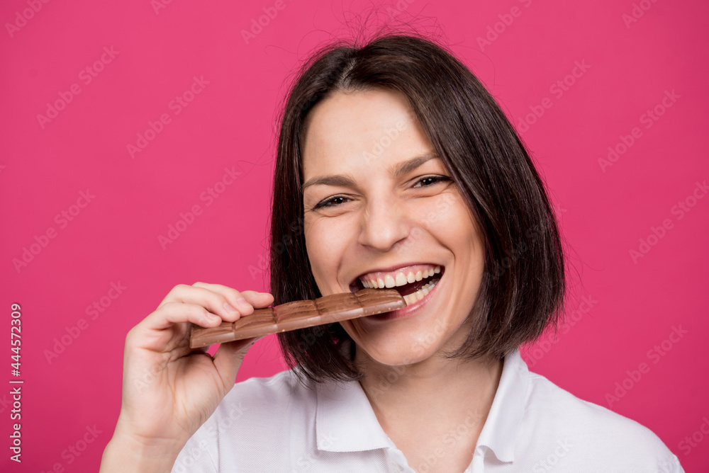 Beautiful young woman bites a bar of chocolate. Beautiful young woman bites a bar of chocolate.