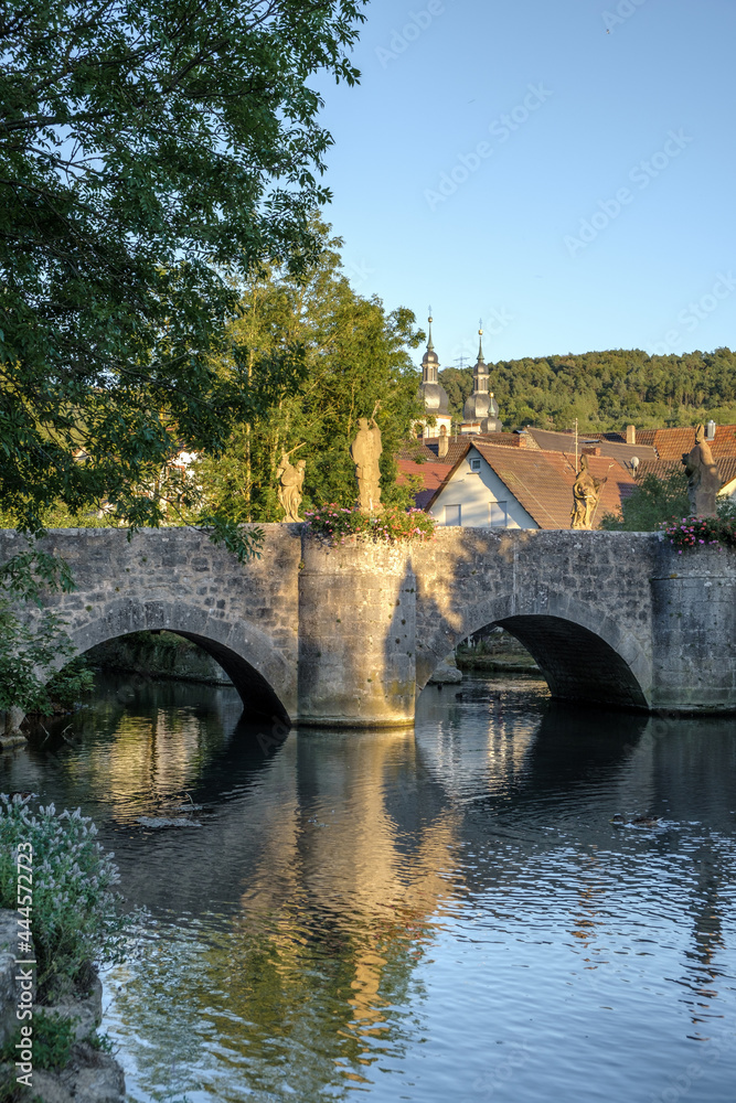 View to the old Grünbach bridge in Gerlachsheim with baroque monastery church in the background.