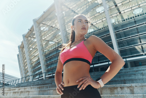 ow angle view of confident young woman in sportswear holding hand on hip