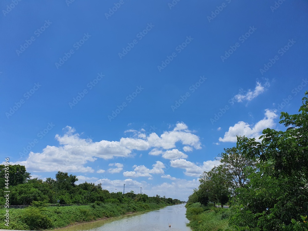 The atmosphere of the irrigation canal There are trees on both sides of the canal, agricultural lifestyle, bright blue sky.