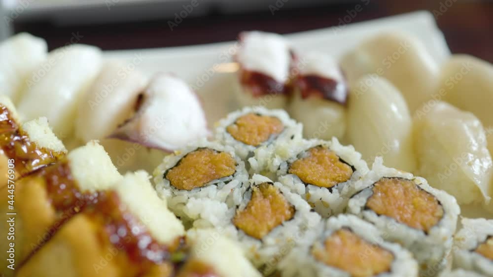 close up view of delicious yummy sushi from a Japanese restaurant. there's a mix of healthy fish maki salmon tuna cucumber shrimp sashimi and avocado. Traditional Asian cuisine close up view of delicious yummy sushi from a Japanese restaurant. there's a mix of healthy fish maki salmon tuna cucumber shrimp sashimi and avocado. Traditional Asian cuisine