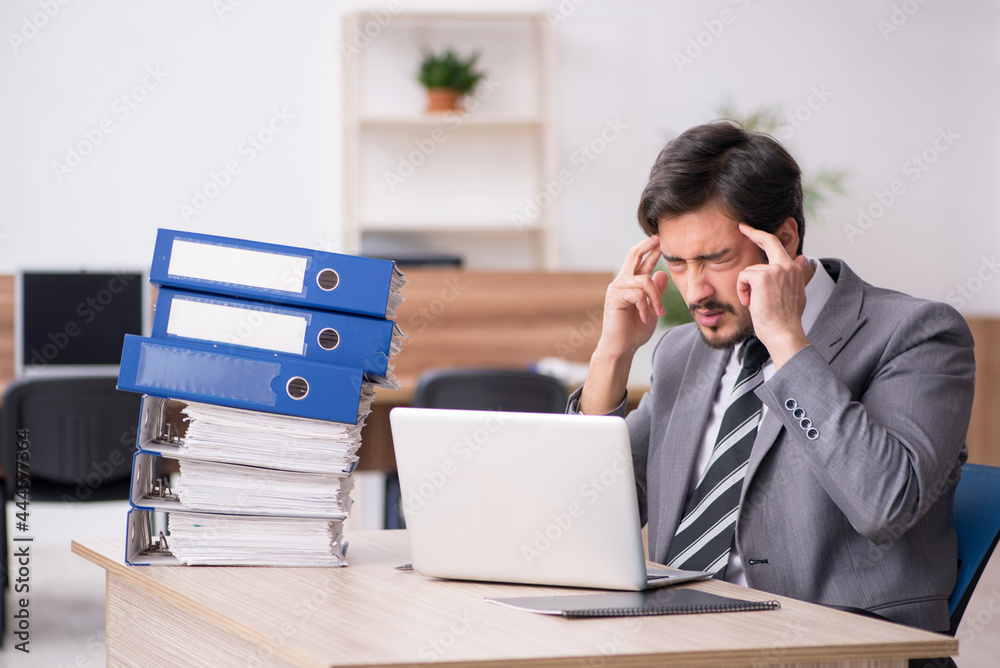 Young male employee unhappy with excessive work in the office