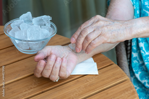 Senior woman holds ice cube on her wrist. How to stay cool in hot weather.
