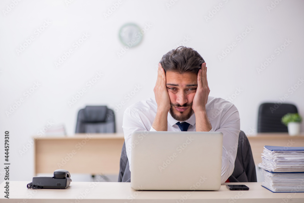 Young male employee and too much work in the office Young male employee and too much work in the office
