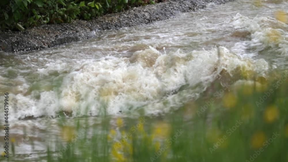 Handheld shot of a strong and fast-moving river, that becoming a raging torrent