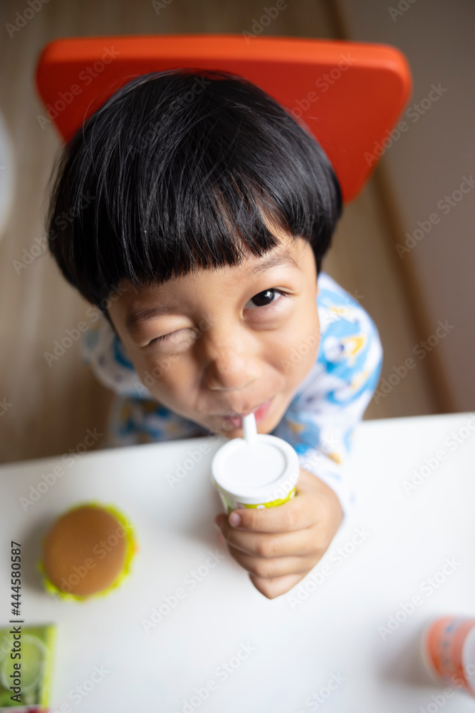 Close-up portrait Asian child boy straight black hair wearing a white pajamas with blue stripes looking at camera of him make funny faces of happy smiling. Advertising childrens products Close-up portrait Asian child boy straight black hair wearing a white pajamas with blue stripes looking at camera of him make funny faces of happy smiling. Advertising childrens products