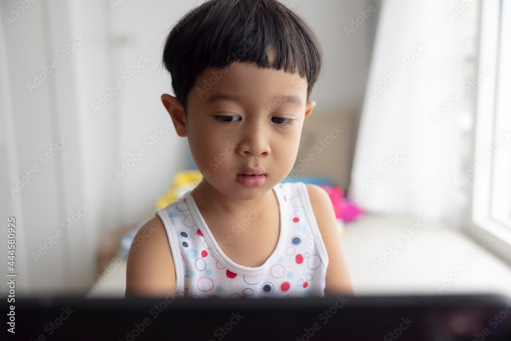 close-up, Asian boy studying through online e-learning system. Have video call distant class with teacher using laptop at home, Covid-19 coronavirus, study online on computer, homeschooling concept close-up, Asian boy studying through online e-learning system. Have video call distant class with teacher using laptop at home, Covid-19 coronavirus, study online on computer, homeschooling concept