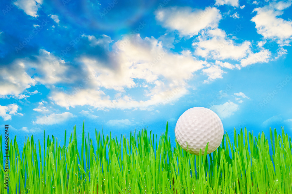 Golf ball on a green lawn against a blue sky with clouds. Golf ball on a green lawn against a blue sky with clouds.