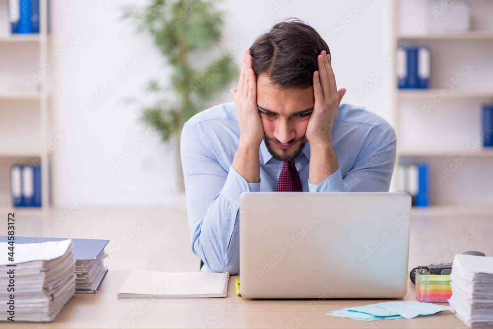 Young male employee and too much work in the office