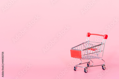 Shopping concept : Red shopping cart on pink background. online shopping consumers can shop from home and delivery service. with copy space