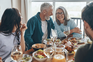 Happy multi-generation family communicating and smiling while having dinner together