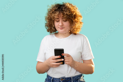 Gadget people. Phone communication. Body positive. Modern technology. Happy cheerful smiling curly hair overweight woman smartphone chatting isolated on blue background.