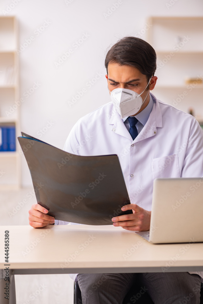 Young male doctor radiologist working in the clinic during pande Young male doctor radiologist working in the clinic during pande