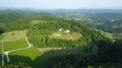 Cinematic view of the drone flying over the green hill. Settlement over the green forest hill. photo