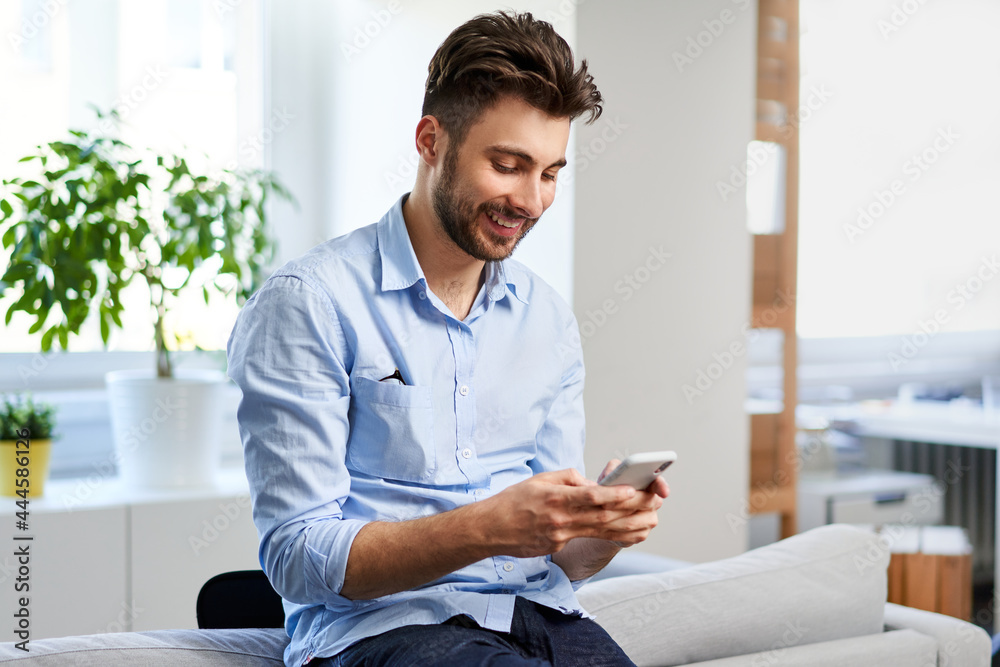 Young man using mobile phone while working from home Young man using mobile phone while working from home