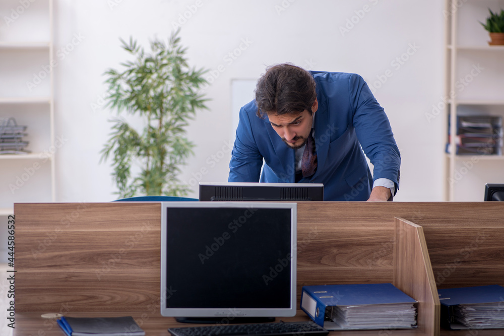 Young male employee sitting at workplace Young male employee sitting at workplace