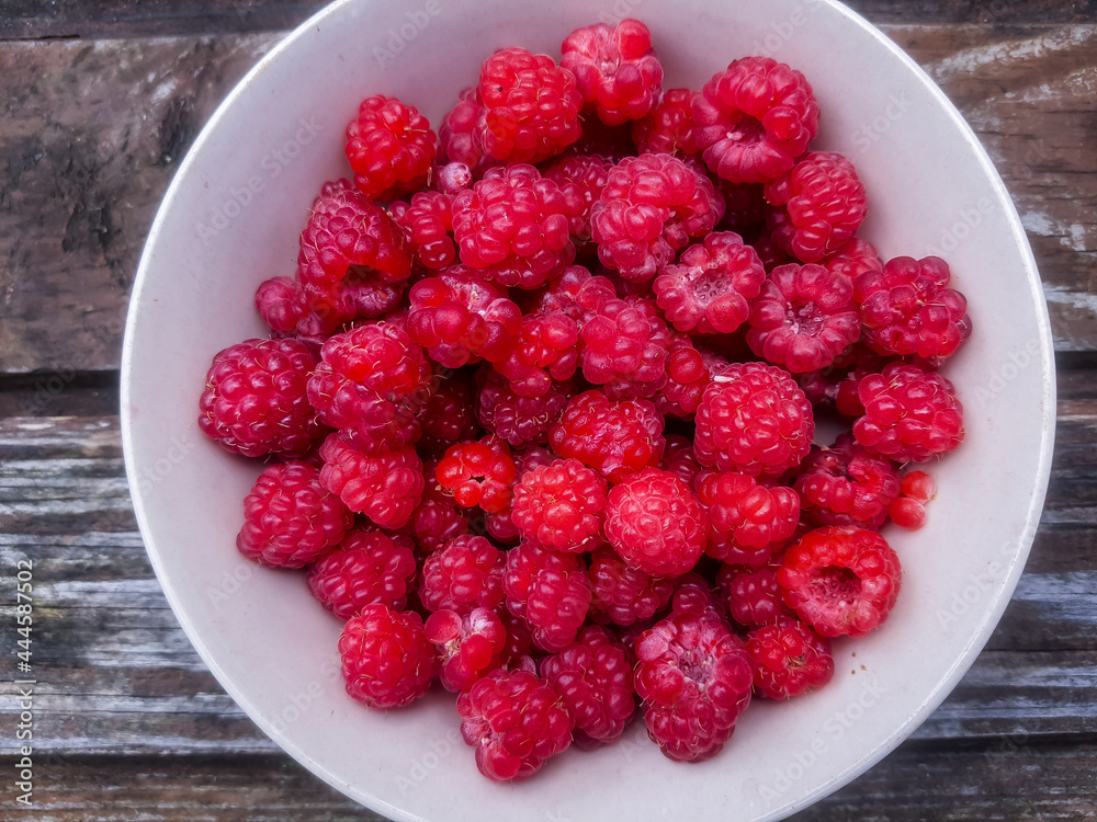 Closeup of bowl of fresh and ripe rasberries on wooden table. natural food.Ripe tasty berries.Natural vitamins. organic summer fruits.