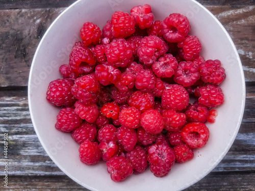 Closeup of bowl of fresh and ripe rasberries on wooden table. natural food.Ripe tasty berries.Natural vitamins. organic summer fruits.