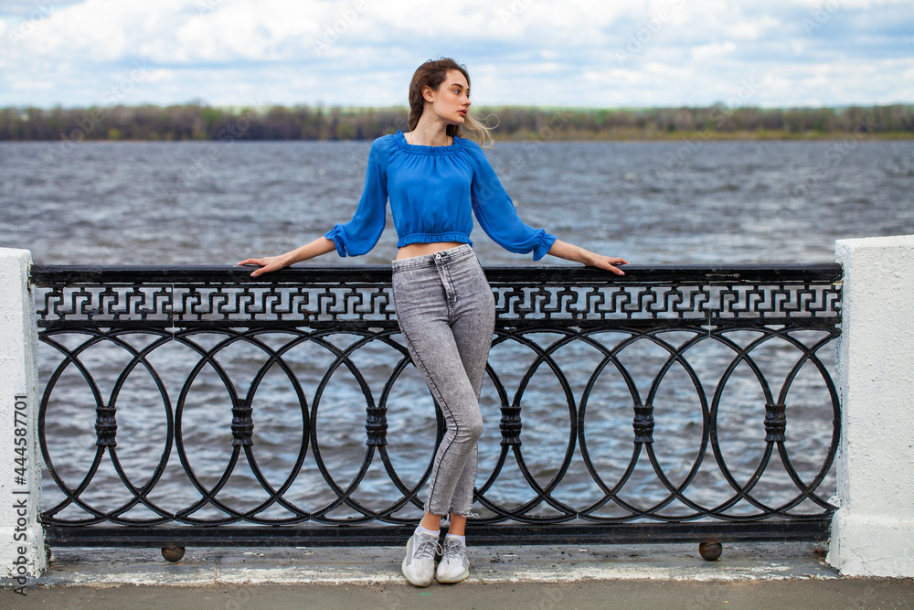 Young beautiful woman in blue blouse and gray jeans Young beautiful woman in blue blouse and gray jeans