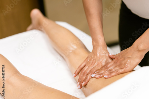 Beauty salon professional pouring oil from a massage candle on the back of his patient.