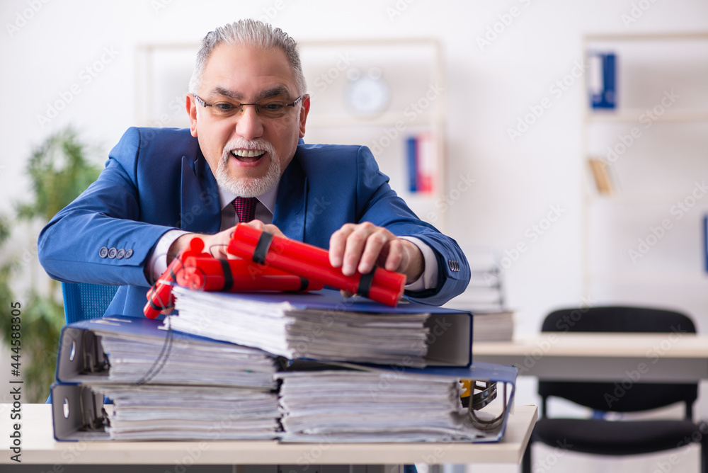 Old male employee with dynamite in the office Old male employee with dynamite in the office