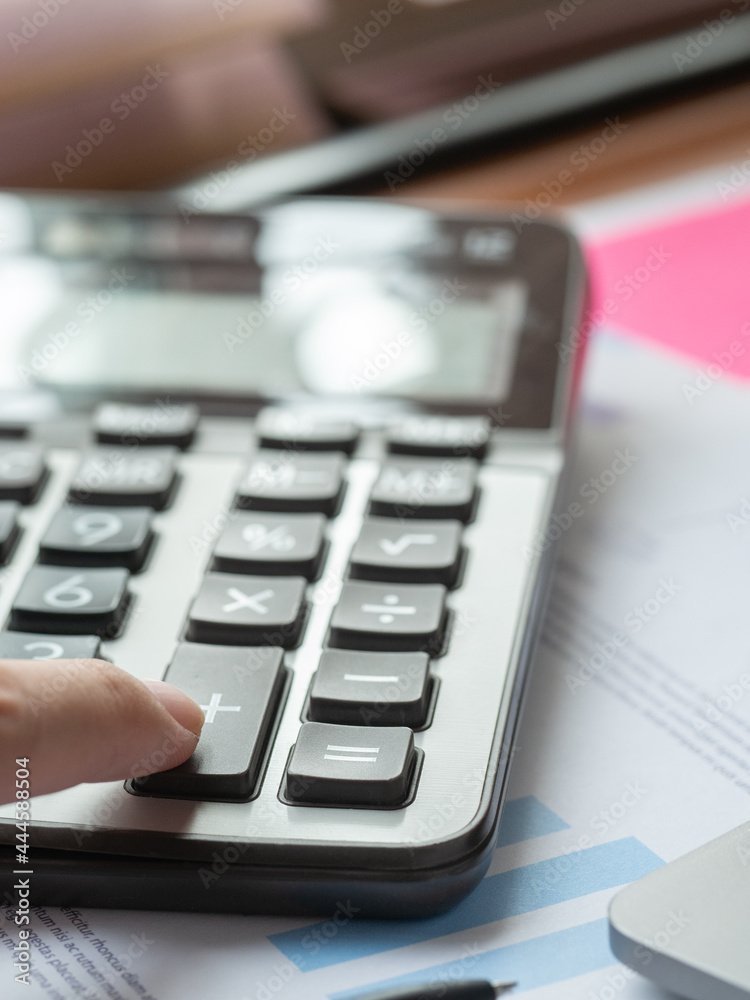 Finger of businessman push on calculator for calculating corporate income tax data And analyzing charts of financial. Investment in finance and accounting concept.
